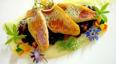 Mullet fillets and black rice with pistachio on sweet and sour sauce with pine nuts and mandarin orange